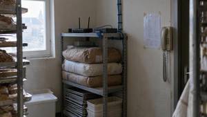 Hinterzimmer einer Bäckerei mit Router auf dem Regal, daneben ein Blatt an der Wand und ein Wandtelefon