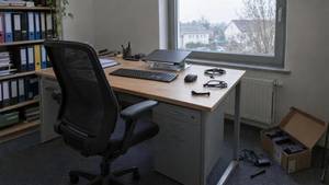 Frisch aufgebauter Arbeitsplatz in einer Hausverwaltung: zugeklappter Laptop auf dem Ständer, Tastatur und Maus, daneben der leere Karton